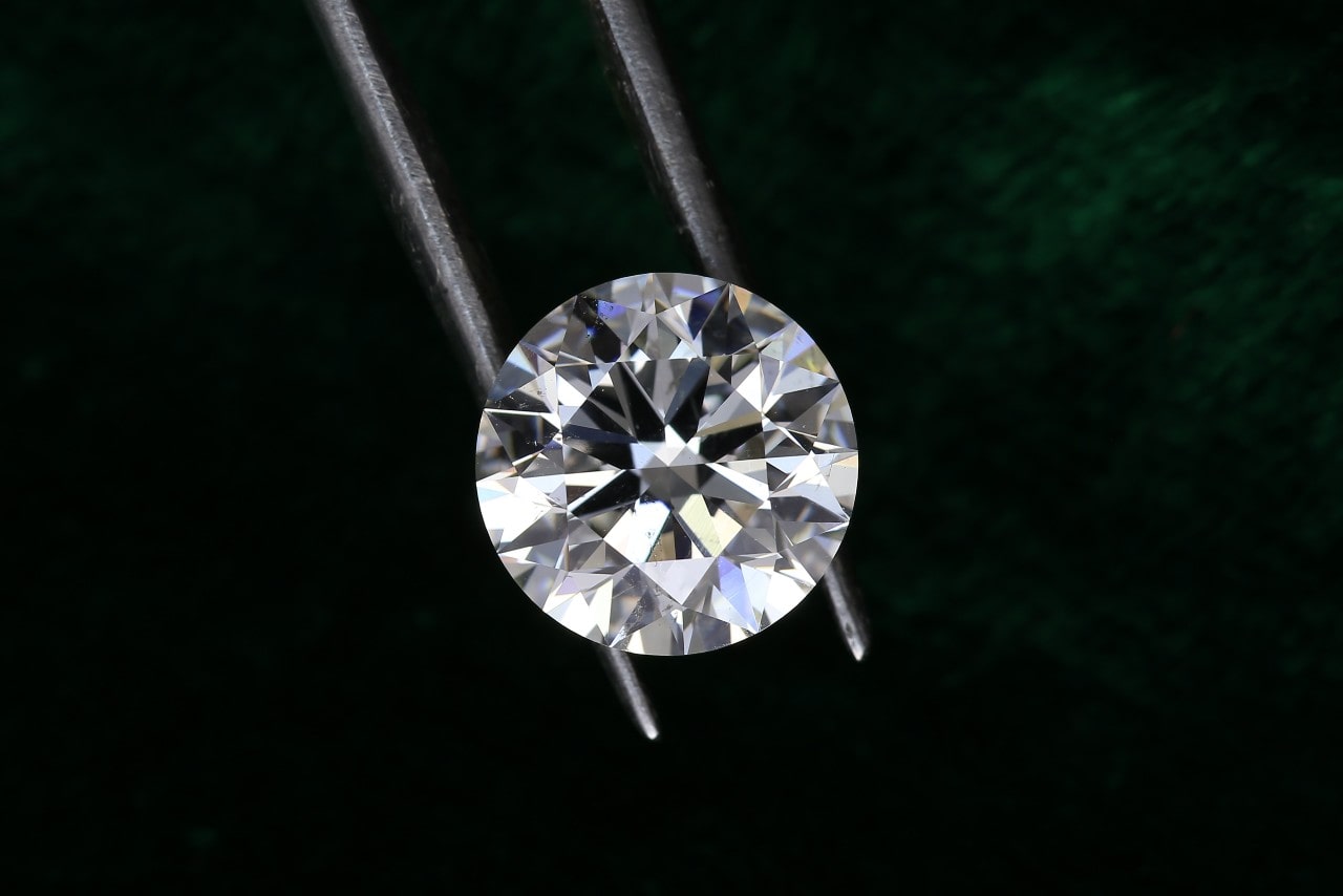 A lab-grown round-cut diamond sits in a pair of jeweler’s tweezers