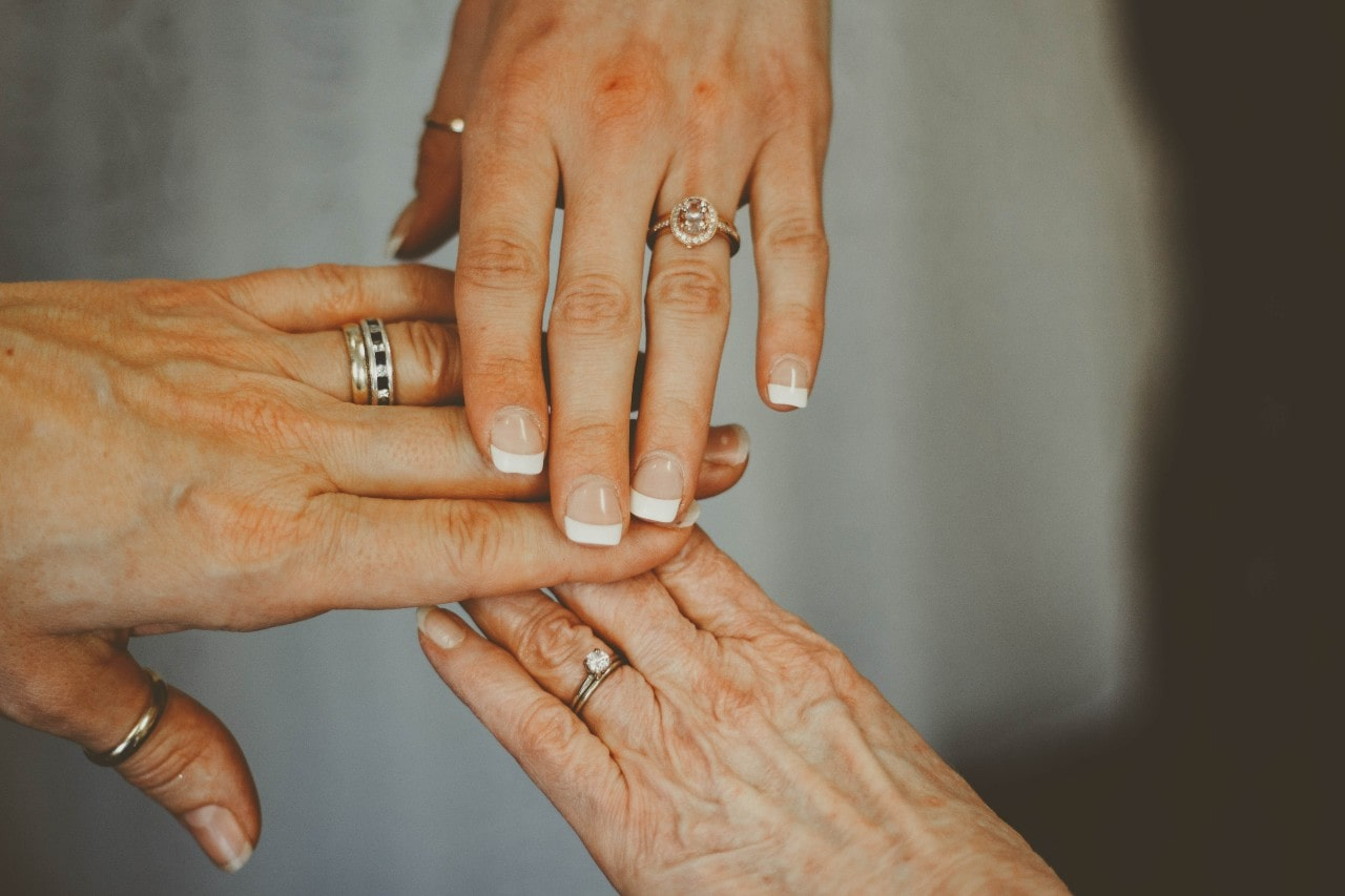 A group of married women stretch their hands out to compare their bridal jewelry