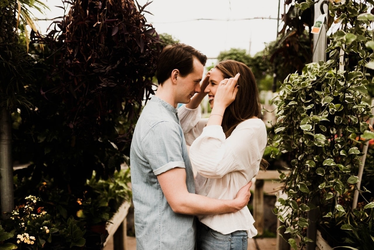 A man grabs his partner by the waist after proposing at a local greenhouse