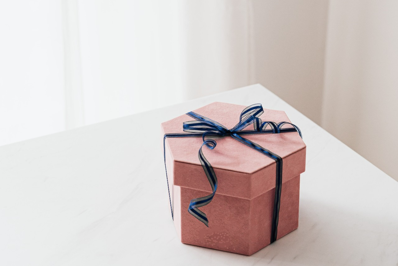 A pink jewelry gift box with a blue ribbon