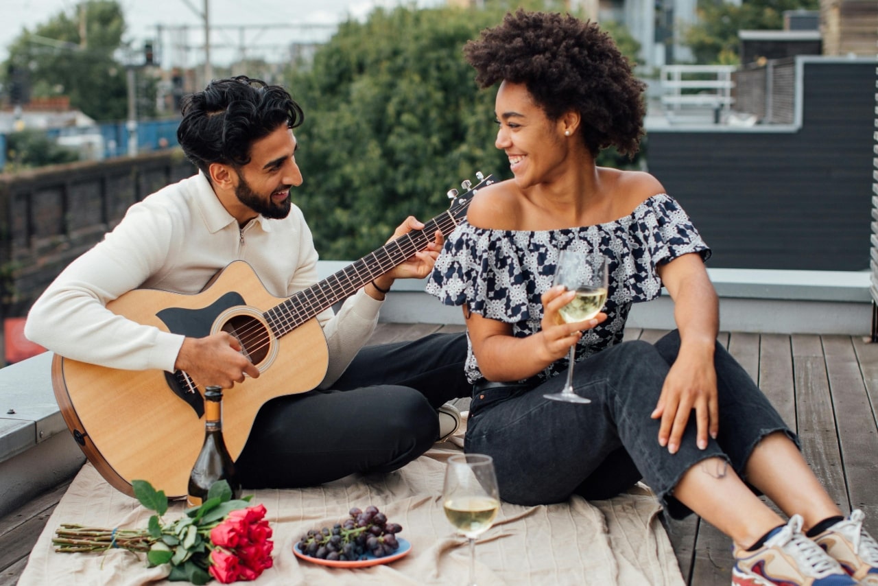 A young couple enjoying a romantic moment on a rooftop, the man playing the guitar for his partner.