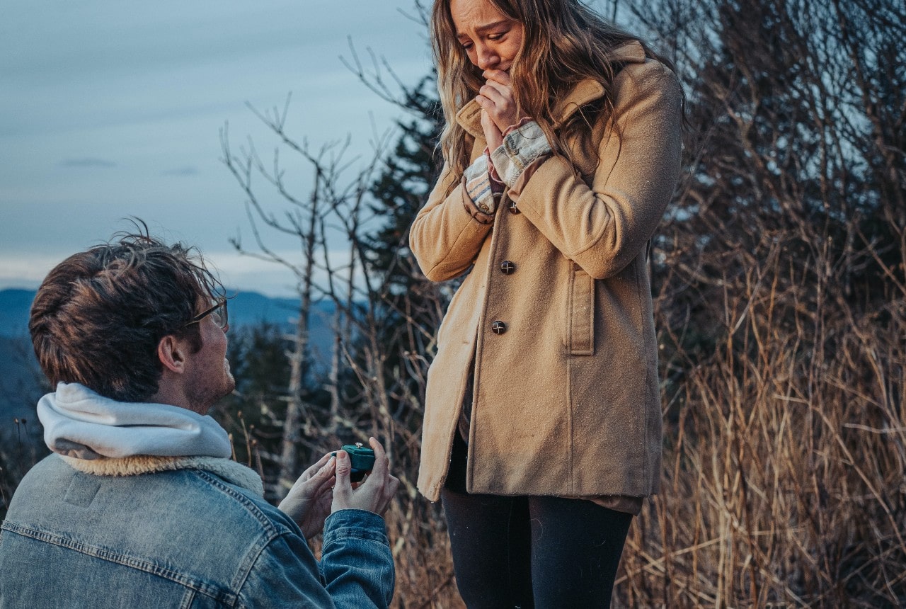 A young woman tearfully accepting her partner’s proposal during the winter months.