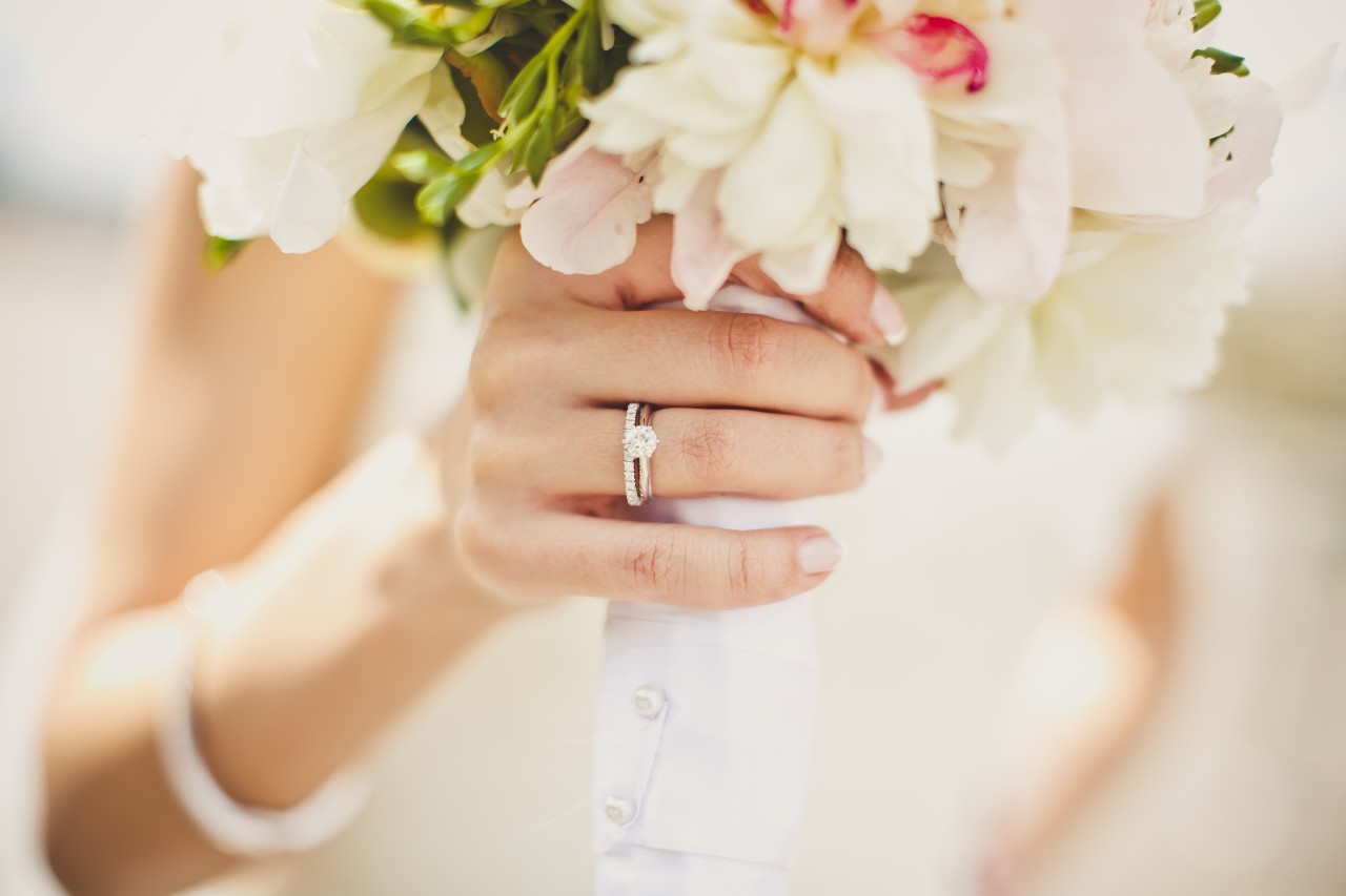 A close-up of a bride’s hand, holding a small but vibrant bouquet.