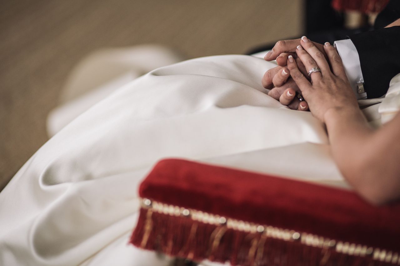 A bride and groom hold hands during their reception.