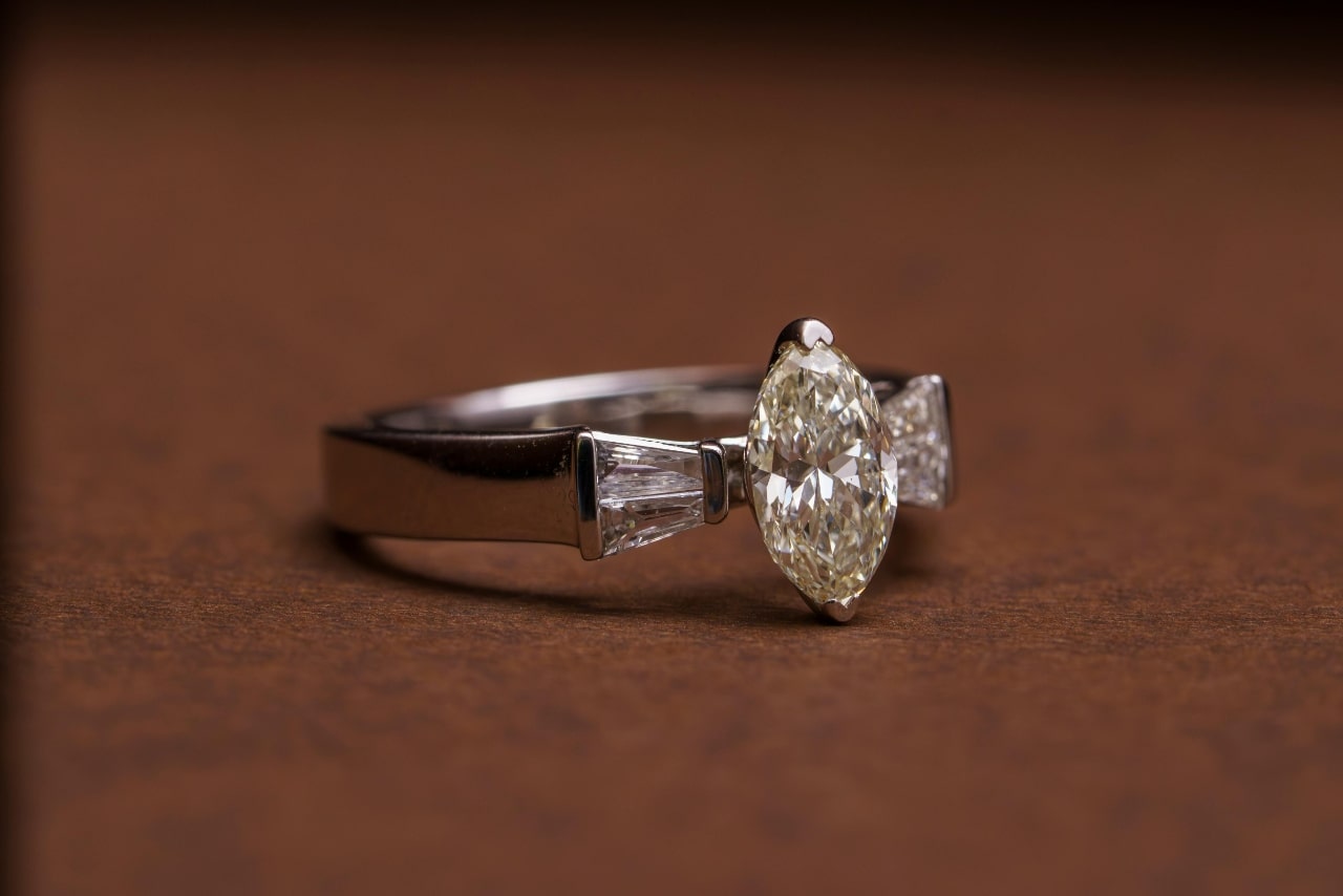 A white gold three stone diamond engagement ring on a brown surface.