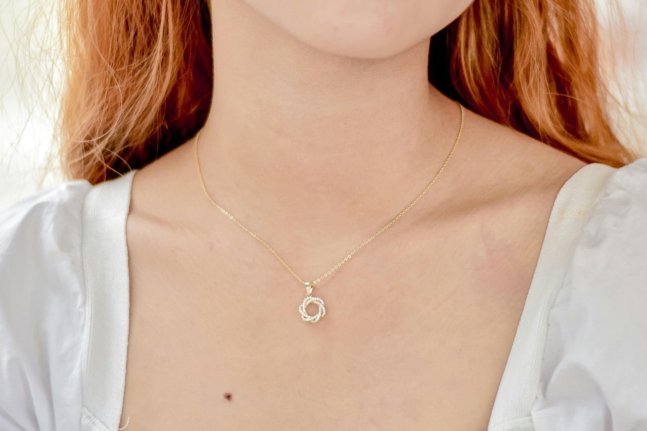 A close-up of a woman’s collarbone, adorned with a delicate diamond necklace.