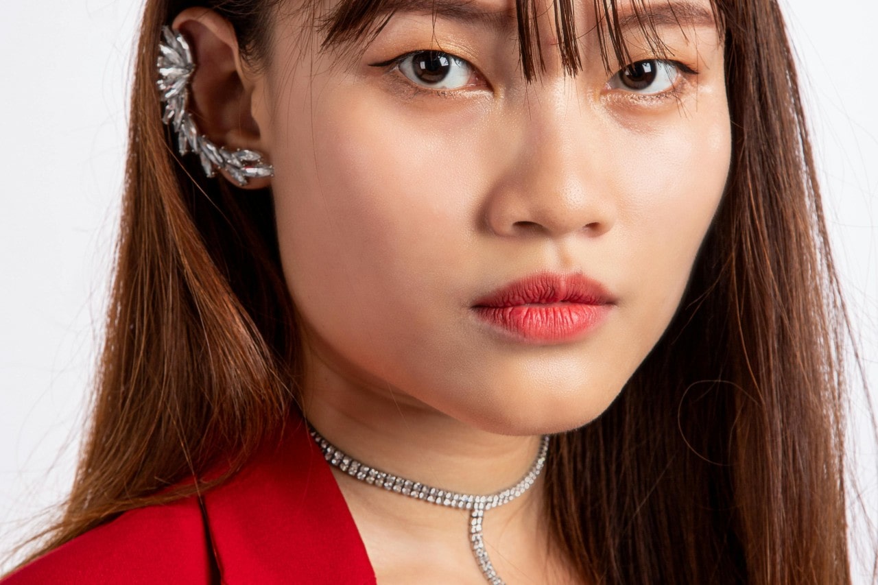 A close-up of an elegant woman wearing a bold diamond choker and ear cuff.