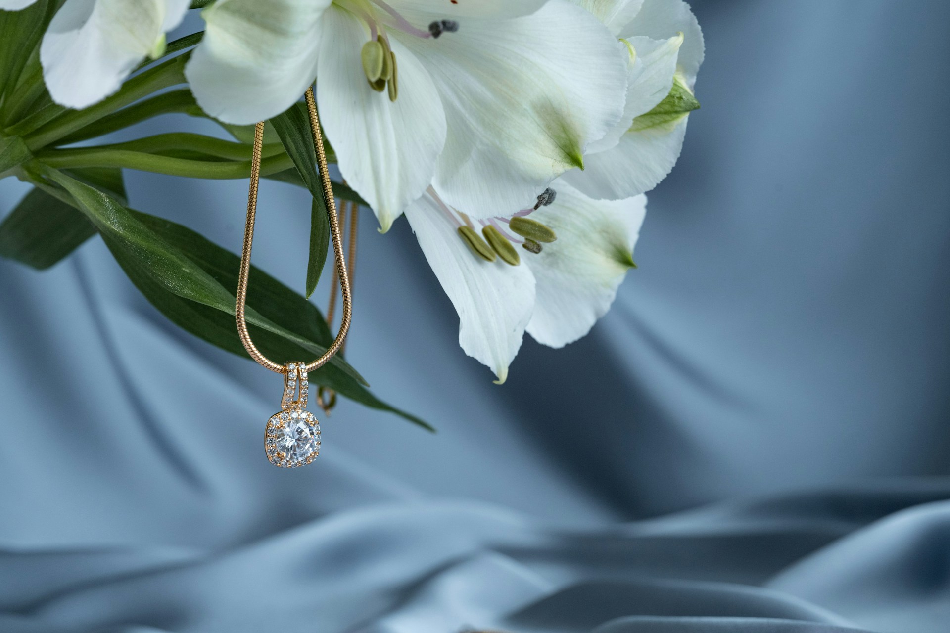 A close-up of a diamond pendant necklace draped from elegant lilies.