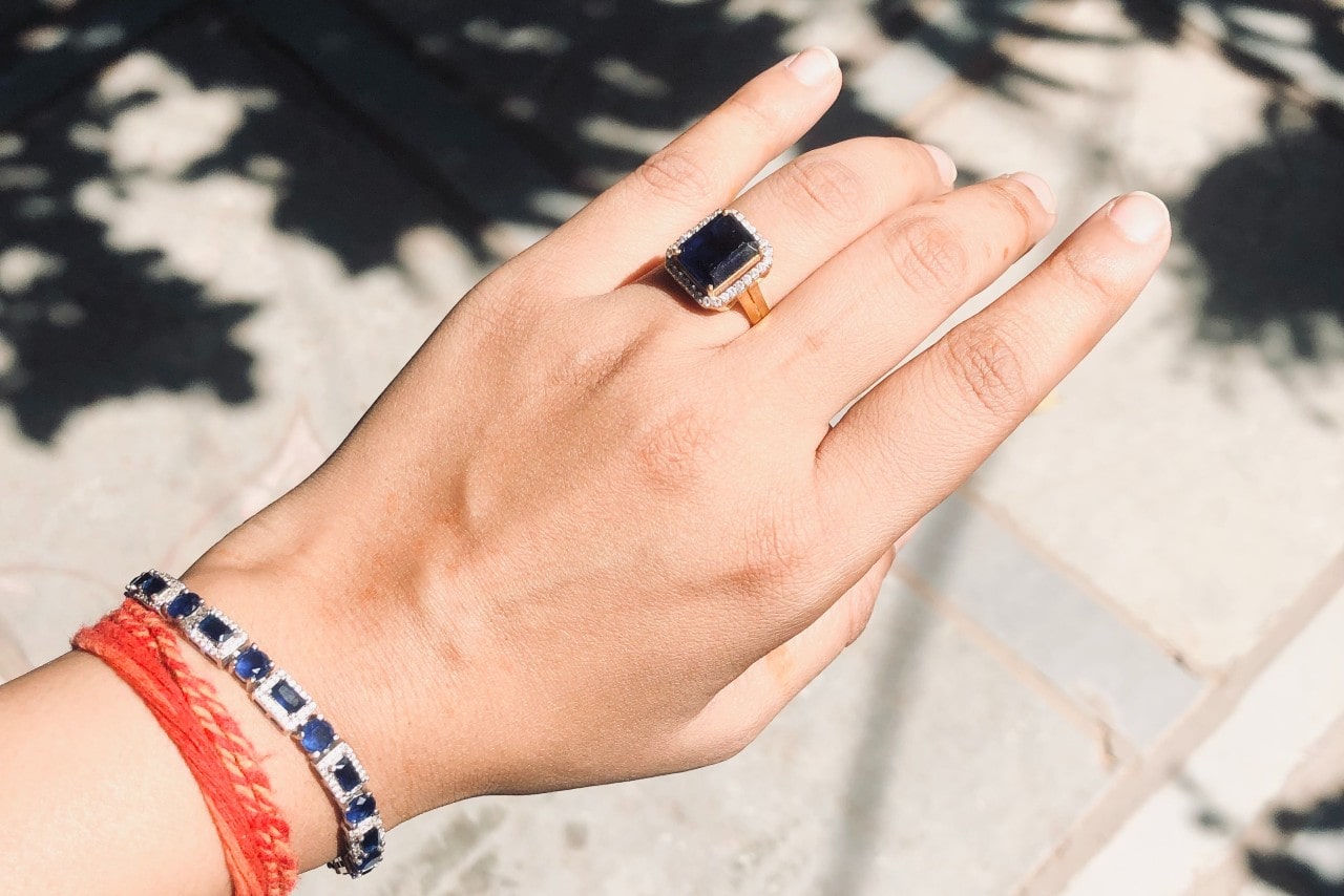 A close up of a hand adorned with matching diamond and sapphire bracelet and fashion ring. A close up of a hand adorned with matching diamond and sapphire bracelet and fashion ring.