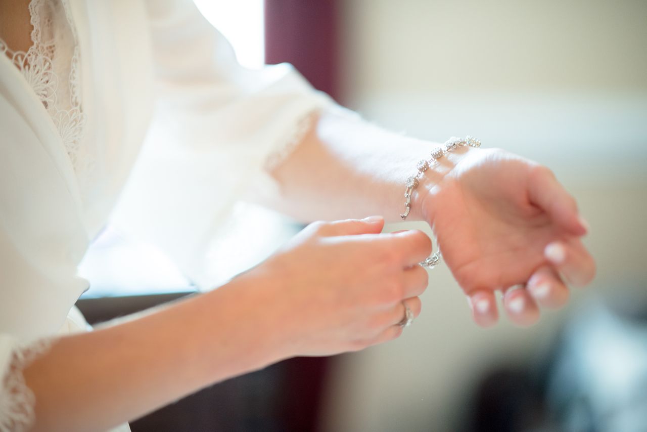 A close-up of a woman putting a diamond bracelet on her wrist.