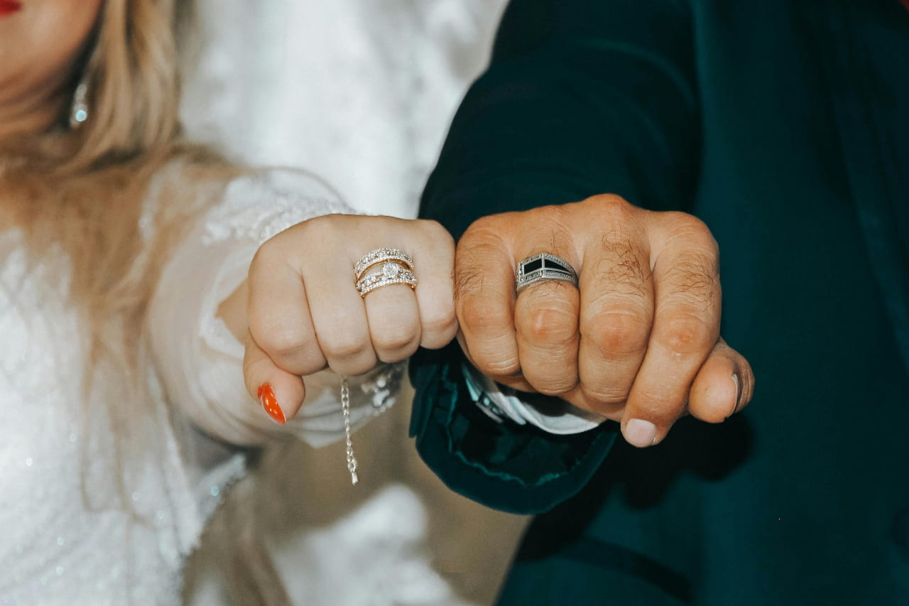 A newlywed couple showcasing their wedding bands side by side. A newlywed couple showcasing their wedding bands side by side.